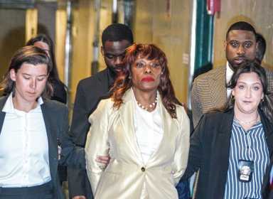 woman in handcuffs escorted by detectives after corruption indictment