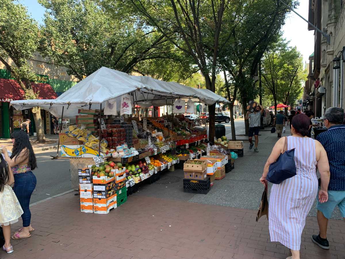 a fruit stand on a sidewalk during the day