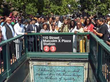 people standing near subway station renamed for Malcolm X