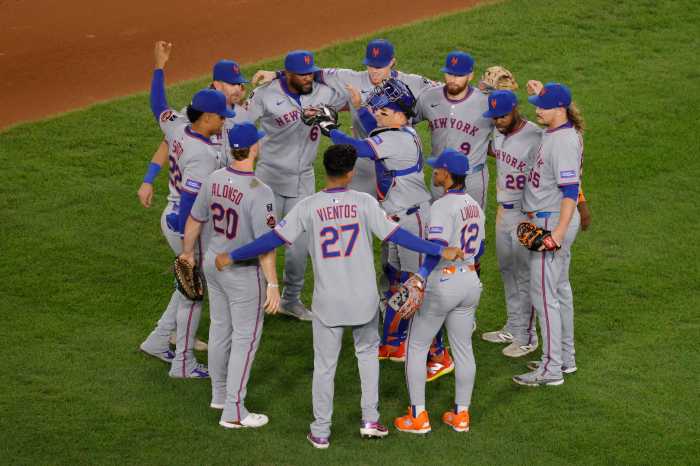 Mets Nationals win: Group of men in grey uniforms huddle on baseball field
