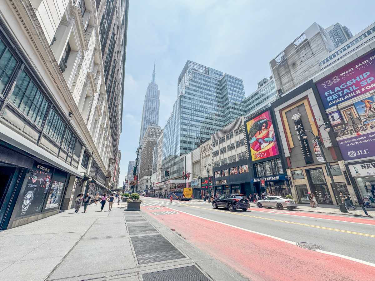 streetscape in Midtown South 34th Street empty bus lane with some traffic and empire state building in background.