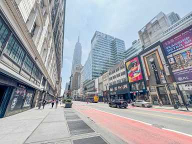 streetscape in Midtown South 34th Street empty bus lane with some traffic and empire state building in background.