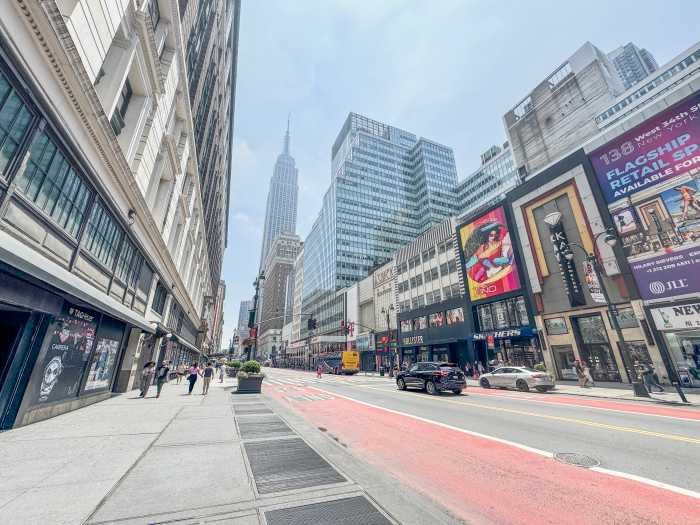 streetscape in Midtown South 34th Street empty bus lane with some traffic and empire state building in background.