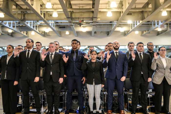 NYPD recruits stand with right arms raised taking an oath
