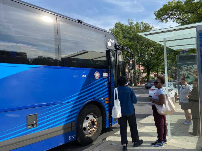 people at a bus stop as a bus arrives