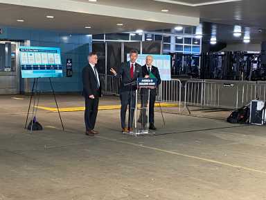 three men in business suits standing at a podium