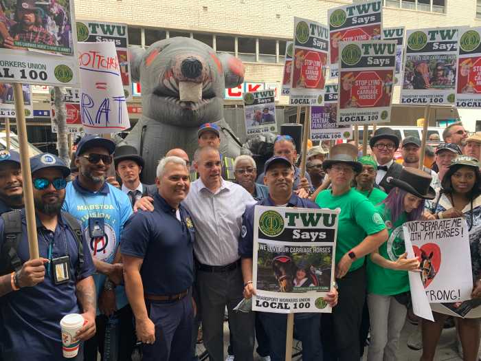 group of people holding signs standing in front of inflatable rat