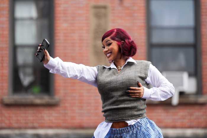 Rapper Cardi B holds a smartphone on the roof of her vehicle as she hosts a pop-up event at a bodega in Washington Heights in New York City, U.S., September 13, 2025. Cardi b will headline Global Citizen Festival