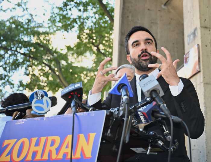 man zohran mamdani gesturing with hands while delivering remarks at press conference
