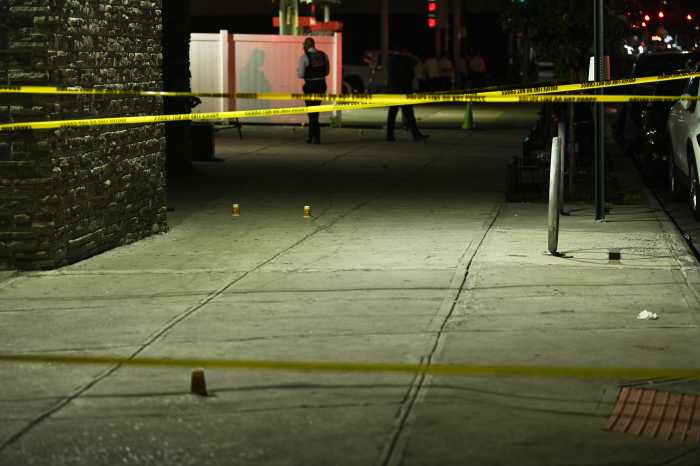 police crime scene tape stretched over sidewalk near shooting scene in Brooklyn