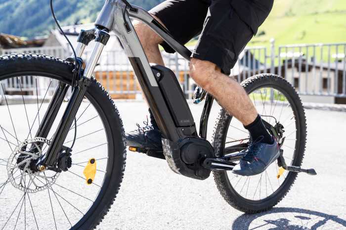 Man Riding E-Bike Bicycle In City. Electric Bike In Summer