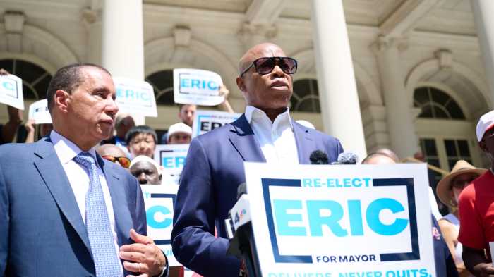 Mayor Eric Adams wearing sunglasses while standing in front of podium