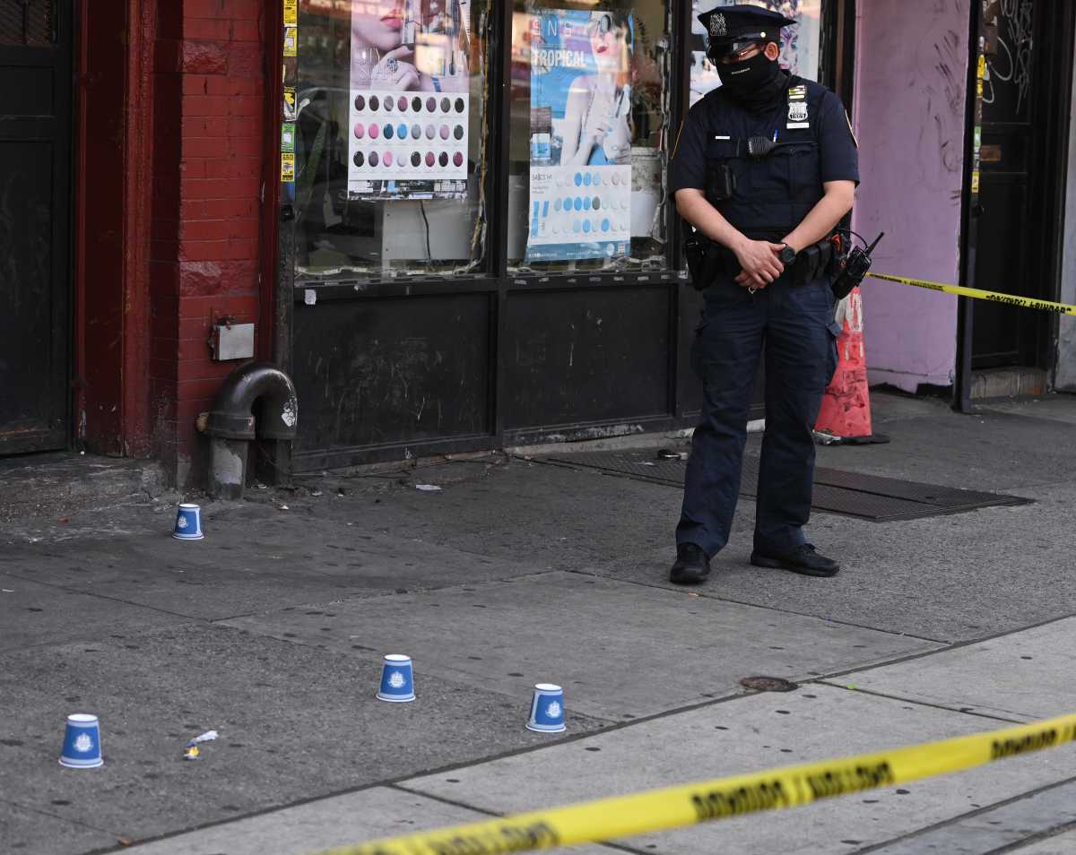 police officer looking at shell casings on ground during Brooklyn shooting investigation