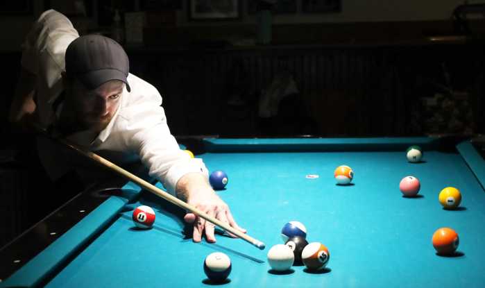 Man plays billiards on pool table found through Chalkysticks