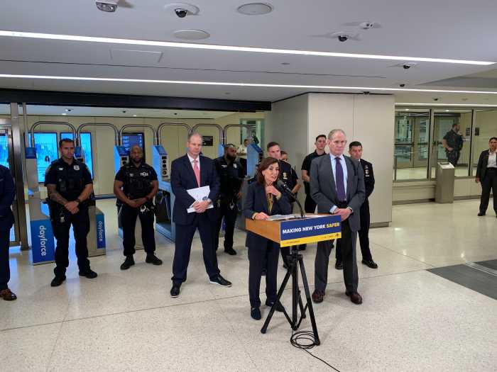 people in suits at a podium in front of subway turnstiles