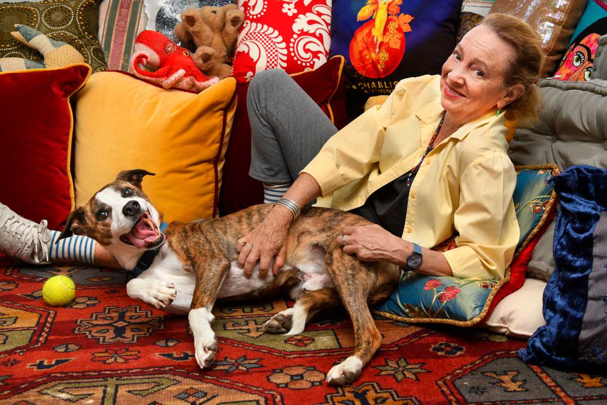 Jamie Bernstein at home lying down while petting her pet dog