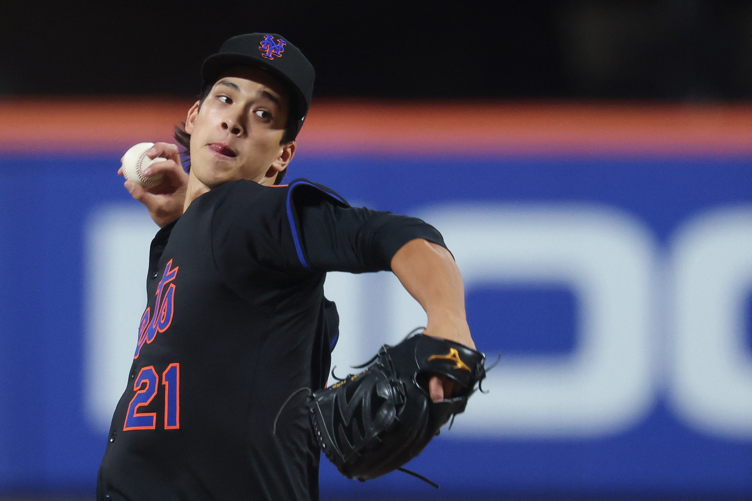 Jonah Tong Mets: Man in black uniform winds up to throw baseball