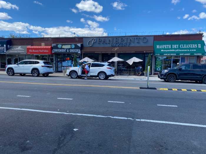 a row of stores in Queens with cars parked in front