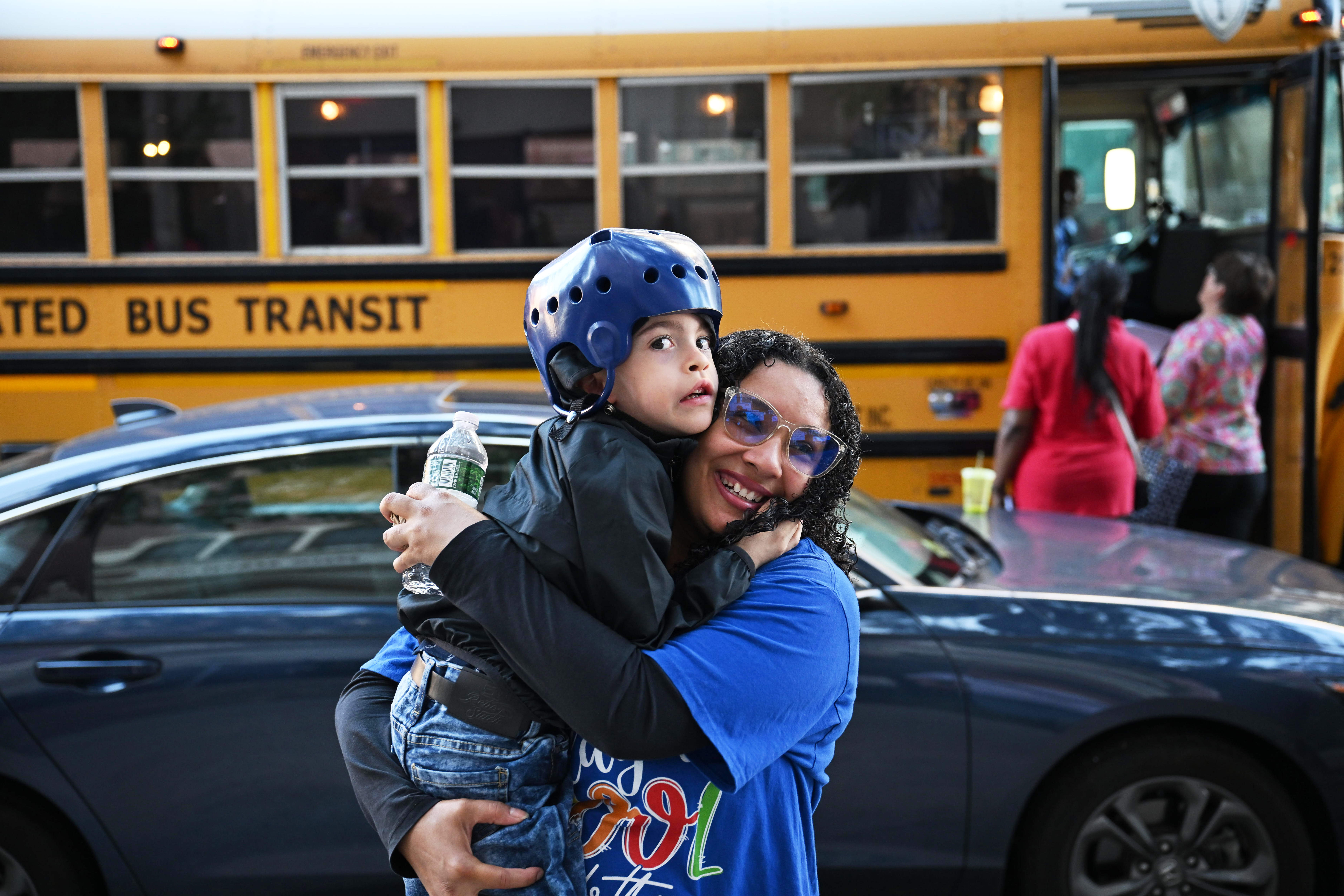 A Para assist a student off the bus for his first day of class.