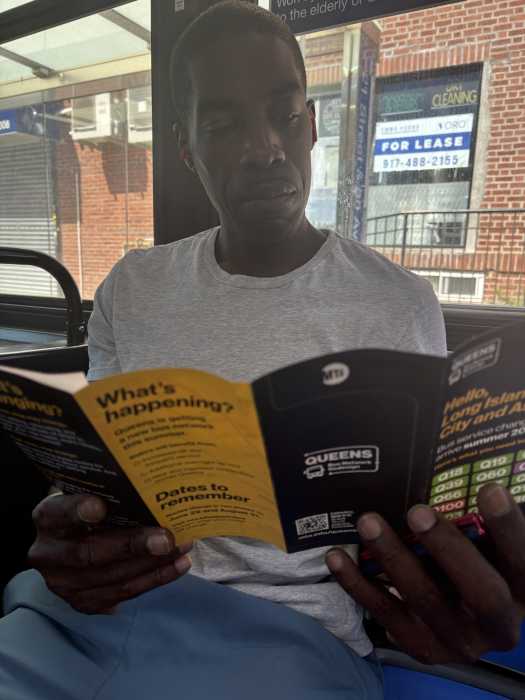 man reading a brochure on a bus in Queens
