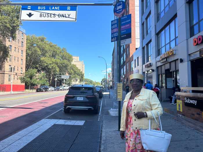 a woman wearing a nicely coordinated outfit waits for a bus in Queens