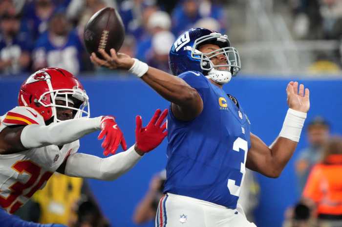 Russell Wilson Giants Chiefs: Football player in blue uniform brings arm forward to throw amid pressure