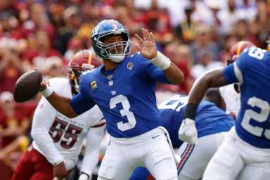 Russell Wilson Giants: Man in blue football uniform and helmet throws ball