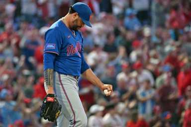 Sean Manaea Mets: Man in blue baseball uniform looks down while walking to mound.