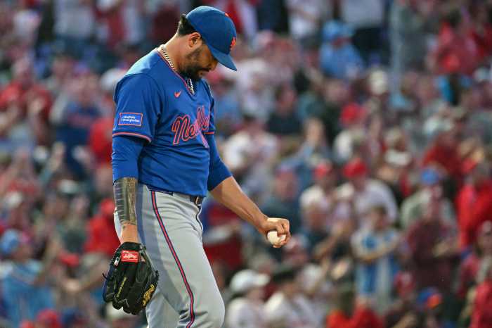 Sean Manaea Mets: Man in blue baseball uniform looks down while walking to mound.