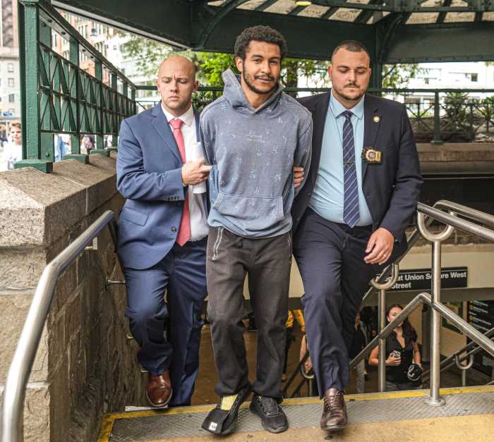 smiling suspect escorted by detectives for subway assault arrest
