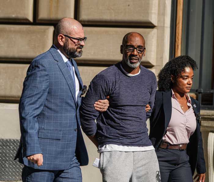 Alleged Queens cold case rape suspect looks at camera while detectives escort him