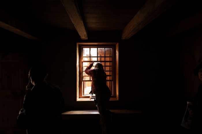 a woman looks out a window in a dark room
