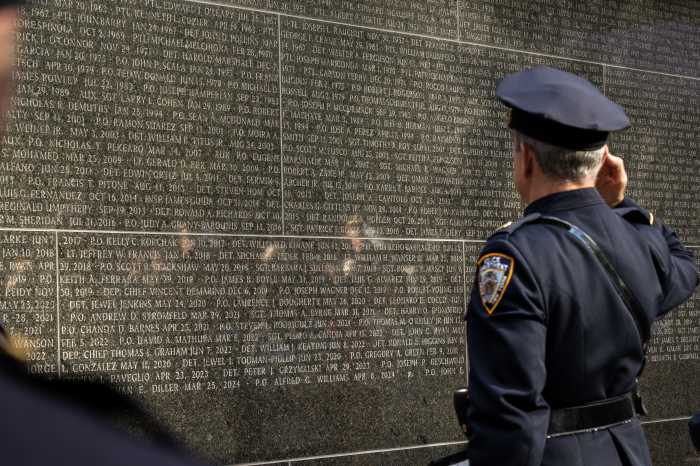 An NYPD officer salutes the name of Jonathan Diller and other officers killed in the line of duty