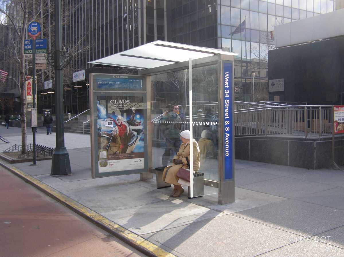 a woman sitting on a bench at a one of the NYC bus stops in the city