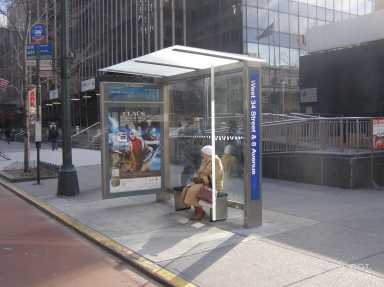 a woman sitting on a bench at a one of the NYC bus stops in the city