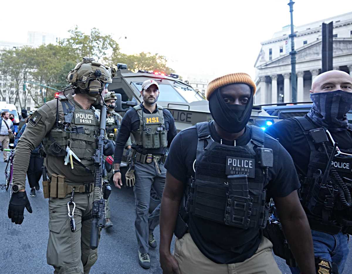 Masked ICE agents near Foley Square after a Chinatown raid on Oct. 21, 2025, with one agent carrying a long rifle. 
