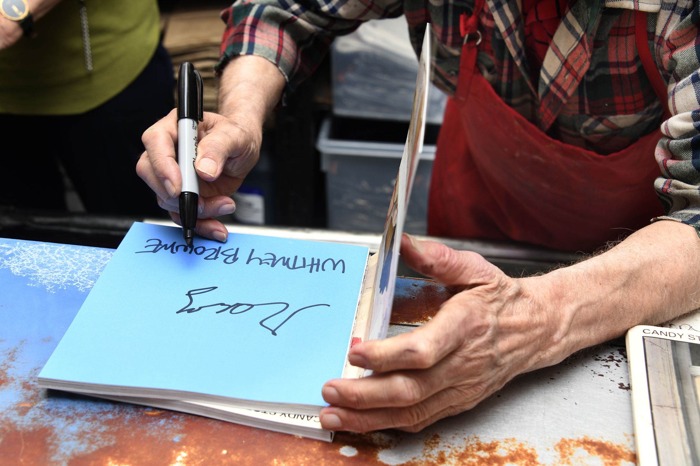 Ray Alavarez signs a copy of Whitney Browne's book "Candy Store"