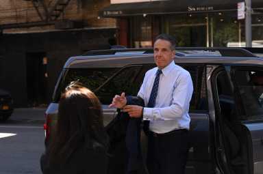 Andrew Cuomo exiting vehicle while putting jacket on