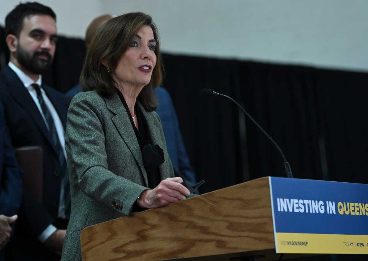 Gov. Kathy Hochul speaking in Queens at podium with Mamdani