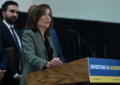 Gov. Kathy Hochul speaking in Queens at podium with Mamdani