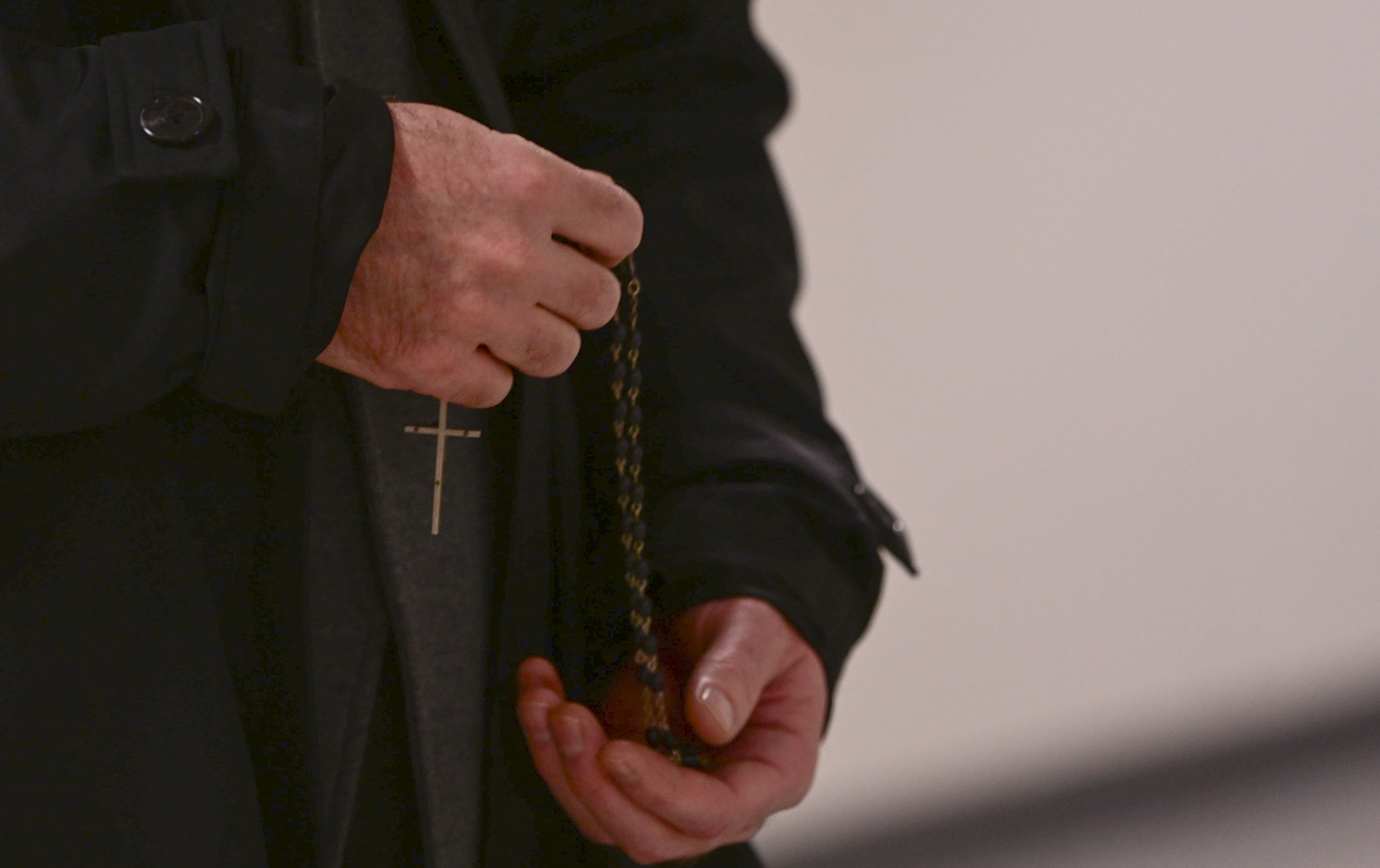 A Priest carries a cross.