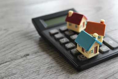 Toy house and calculator with copy space. Property, home insurance, buy, sell and rent concept.