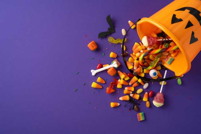 Things to do this weekend in NYC, Oct. 31-Nov. 2 1 Orange pumpkin bucket with various colorful candies spread out on a purple surface