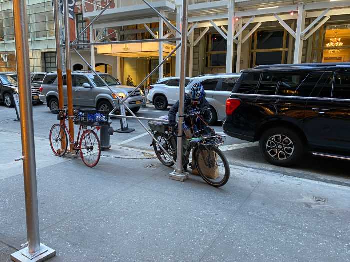 two bikes on a city street lined with cars