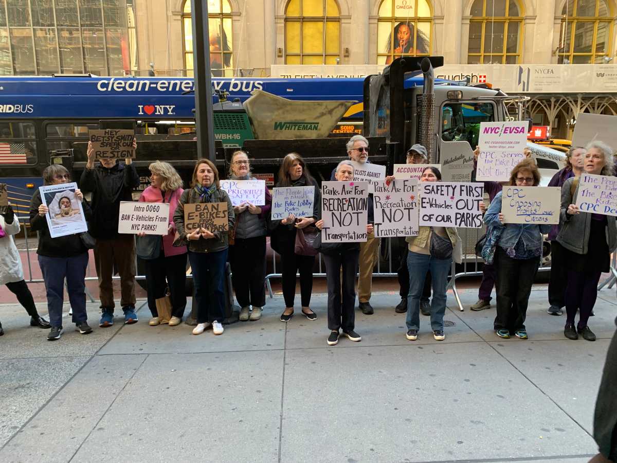 group of people holding signs on a city street near Central Park