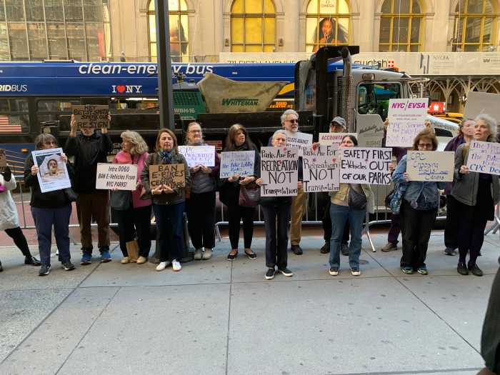 group of people holding signs on a city street near Central Park