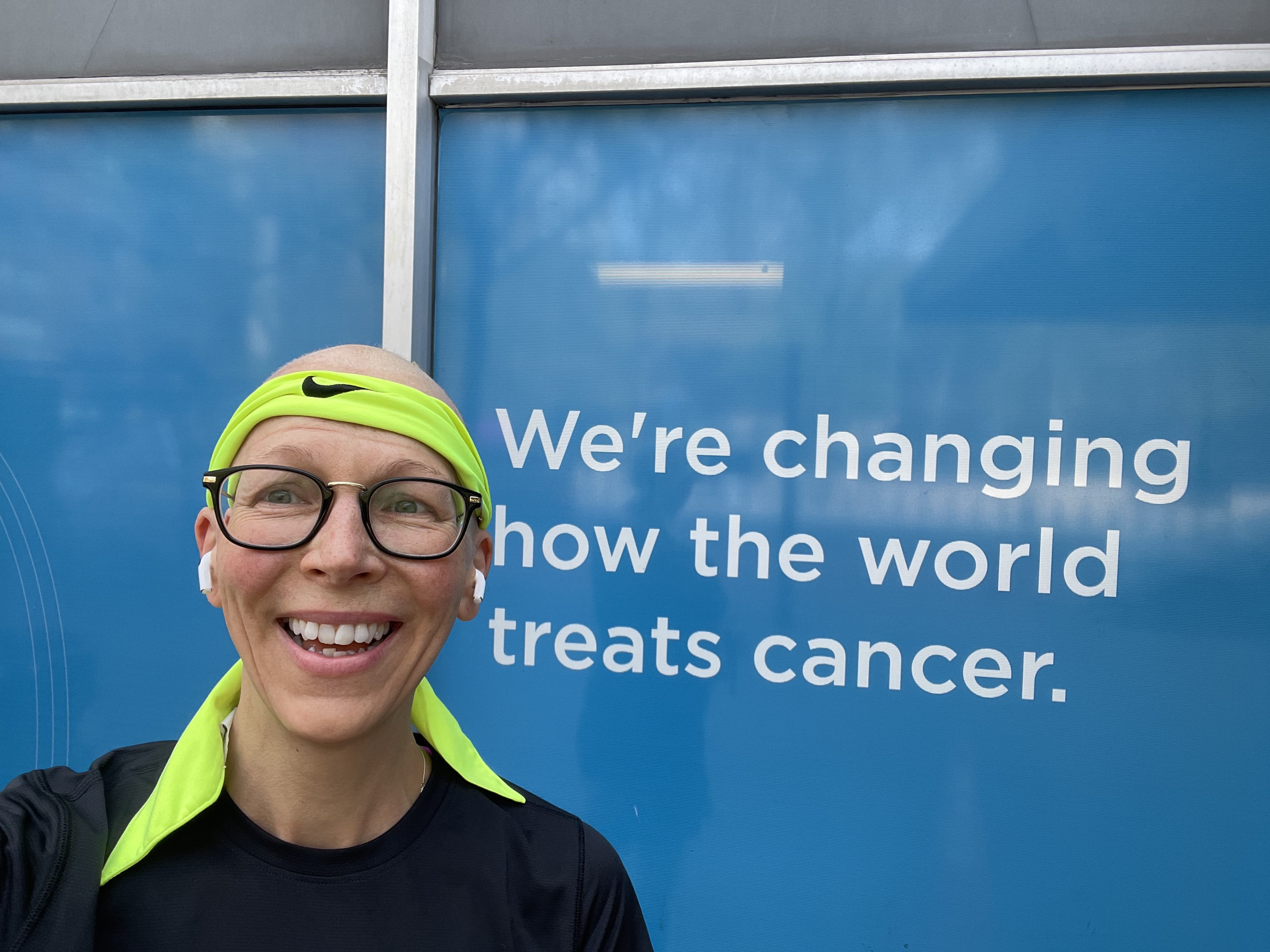 NYC MARATHON | Cancer won't stop Pauline Larkin from running 4 Pauline Larkin in front of a sign that reads "we're changing how the world treats cancer"