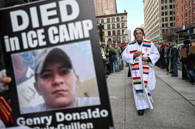 priest walks around federal plaza near poster of ICE detainee