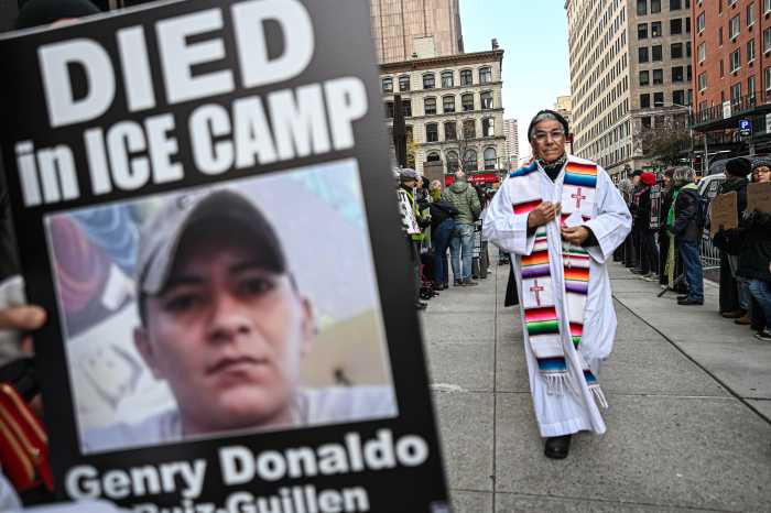 priest walks around federal plaza near poster of ICE detainee