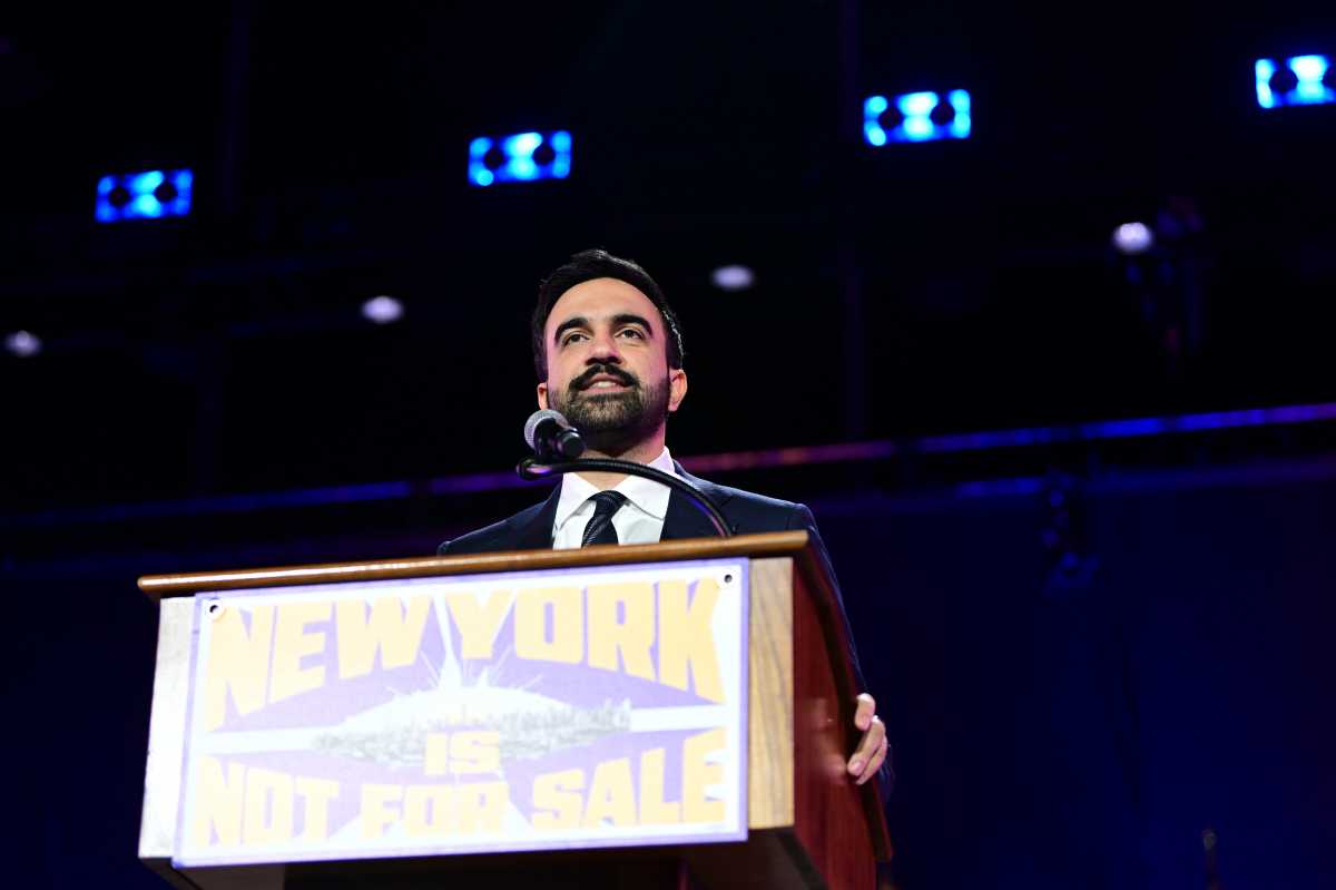 Mayoral candidate Zohran Mamdani speaking at a podium with the banner New York is Not For Sale